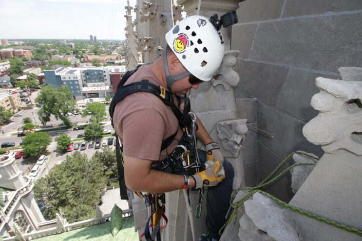 man inspects a piece of stone during a rope access inspection