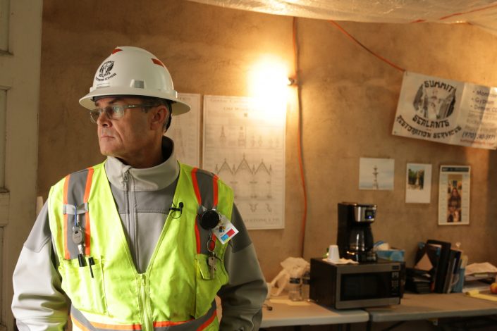 man looks outside window from construction office