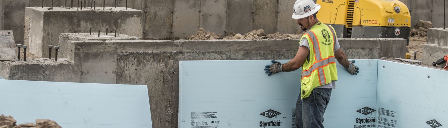 construction worker puts insulation on a concrete foundation