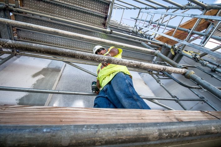 Man walks on scaffolding with drill