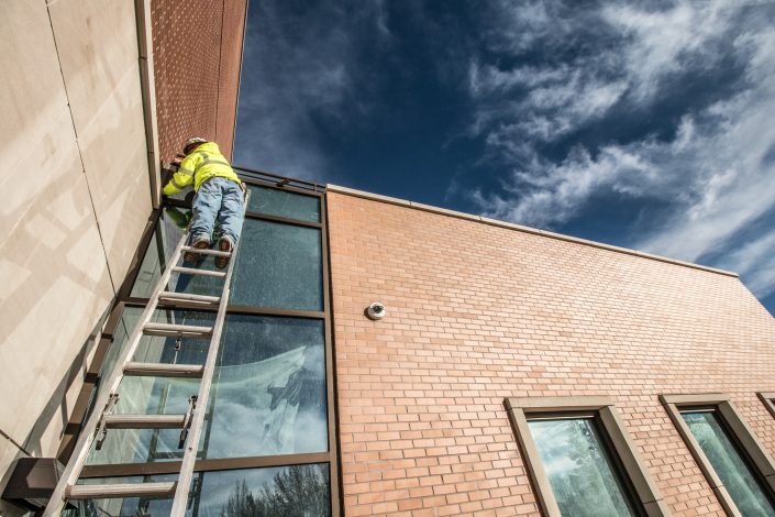 Worker on ladder under a blue sky