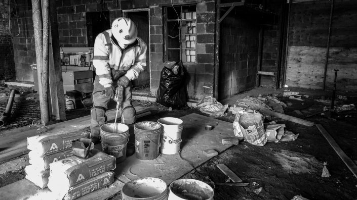 a worker mixes mortar in a bucket