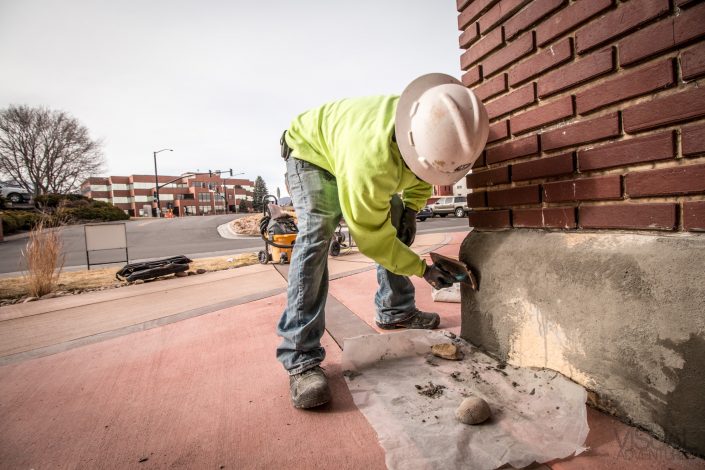 worker repairs concrete on a historical brick building
