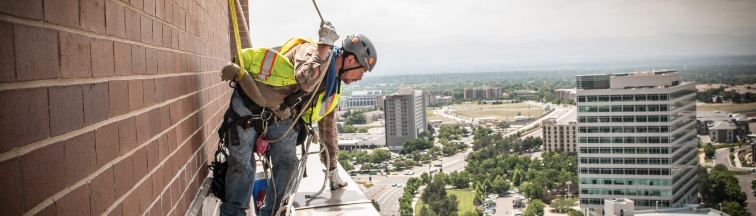 a worker leans over the edge of a building