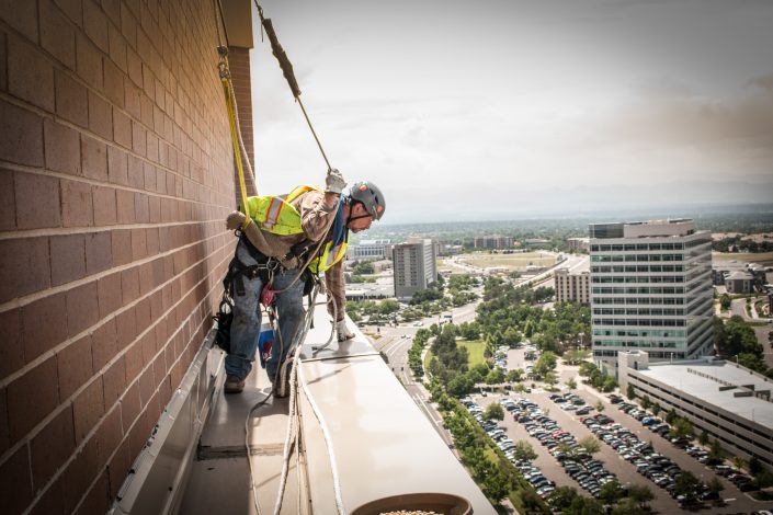 a worker leans over the edge of a building