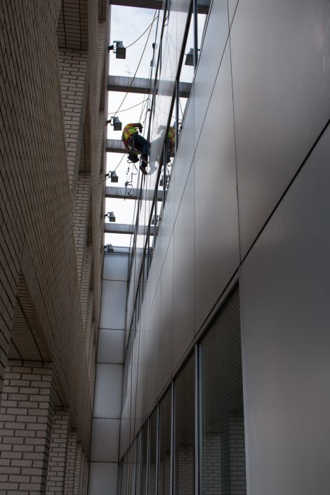 worker seals a window while on a rope