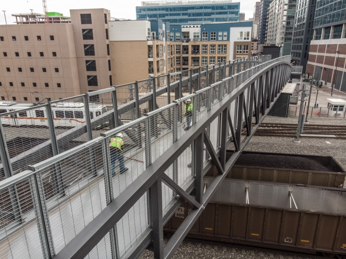 Worker applies a top coat of deck coating to a pedestrian bridge