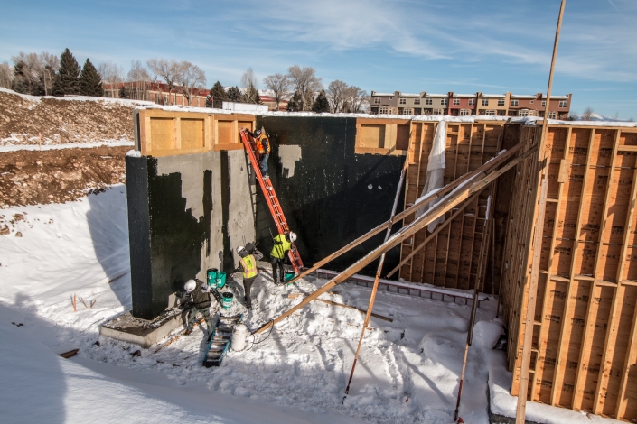 Workers apply Cold fluid applied polyurethane based waterproofing in winter