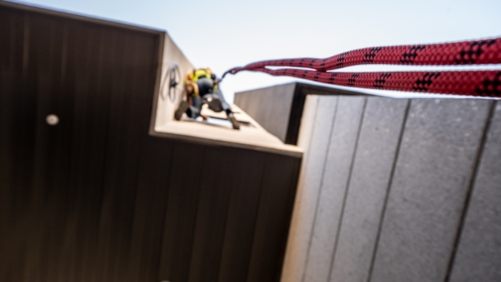 a rope dangles in space as a construction worker is suspended on the side of a building